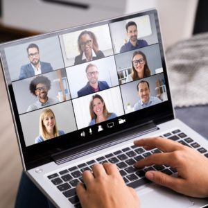 hands typing on laptop keyboard screen showing video conference call