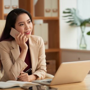 Business woman sitting at desk using mobile phone